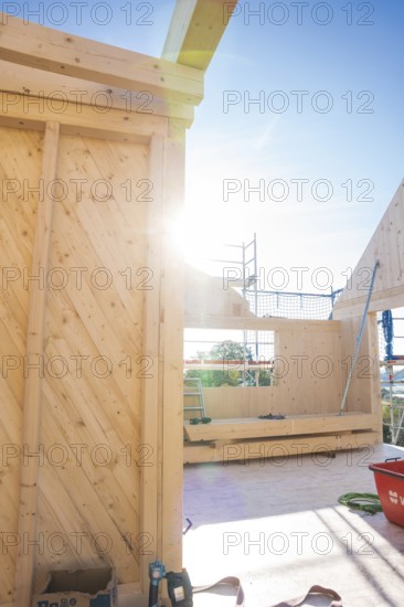 Sunlight floods the construction site's timber structure with visible scaffolding, Timber House