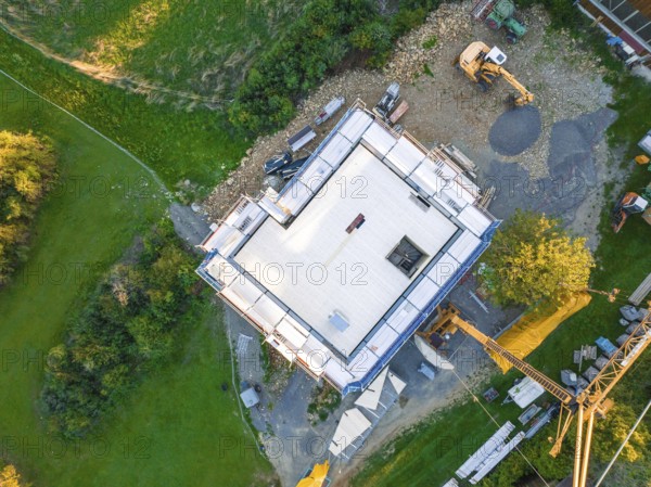 Aerial view of a construction site with building foundation and crane in a green landscape, timber