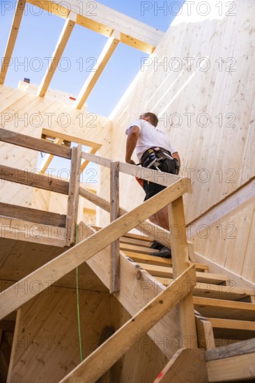 Workers climbing a wooden staircase in a partially converted building, timber house construction,
