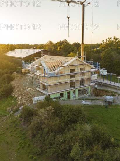 Building under construction, surrounded by scaffolding, at sunset in a rural area, timber house