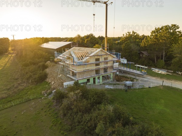 Building under construction at sunset, surrounded by nature in a rural location, timber house