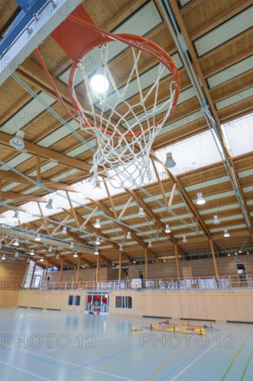 A basketball hoop in a sports hall with wooden structure and neon lighting, Schlehengäu Sporthalle
