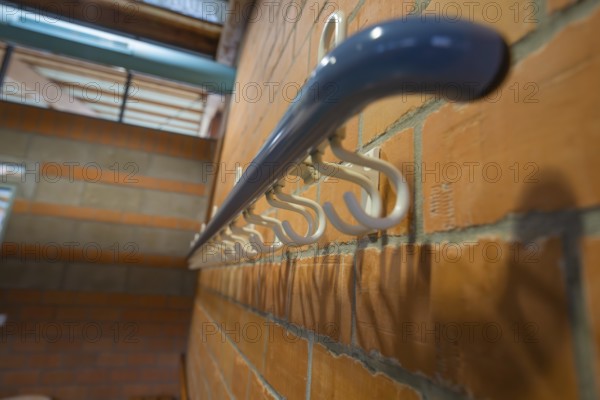 White coat hooks on a brick wall from a close perspective, Schlehengäu Sporthalle Gechingen, Calw