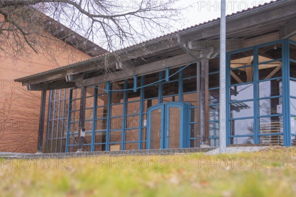 Modern architecture with large glass windows and wooden elements next to a wooded area, Schlehengäu