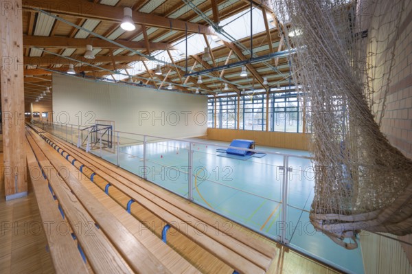 View over the stand of a sports hall with wooden structure and playing field, Schlehengäu