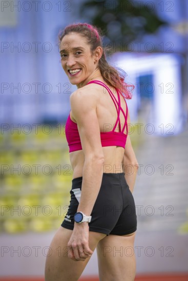 Woman in sporty clothes turns around and smiles, satisfied and relaxed, middle distance runner