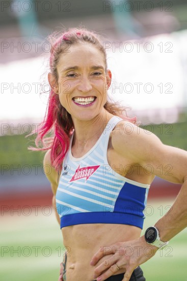 Woman smiling friendly with a wristwatch on in the stadium, middle distance runner Katharina