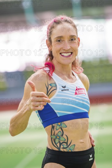 Woman showing thumbs up and smiling with tattoos in stadium, middle distance runner Katharina