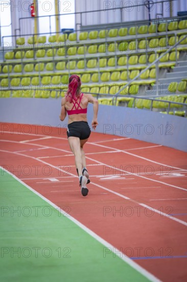 Female athlete concentrated while running, career lines in focus, middle distance runner Katharina