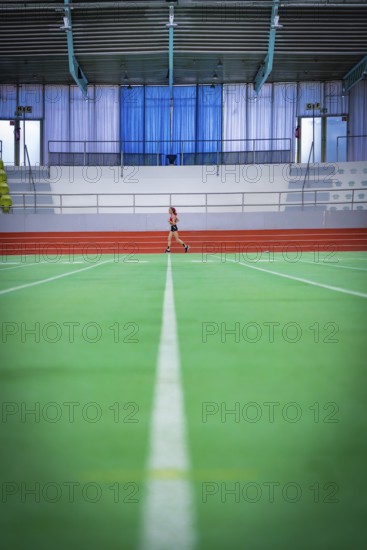 Wide-angle view of an empty track with a person running in the background, middle distance runner