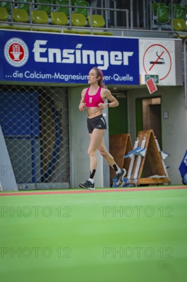 Female athlete running past a banner in a hall, middle distance runner Katharina Jaiser,