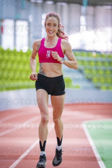 Sporty woman running on a running track in a modern sports hall, middle distance runner Katharina