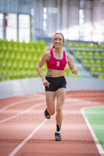 Sportswoman smiles and shows joy while running on an indoor track, middle distance runner Katharina