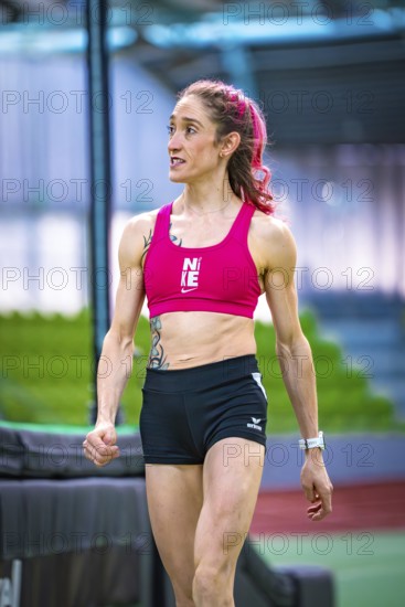 Woman wearing sporty clothes indoors showing determination against green background, middle