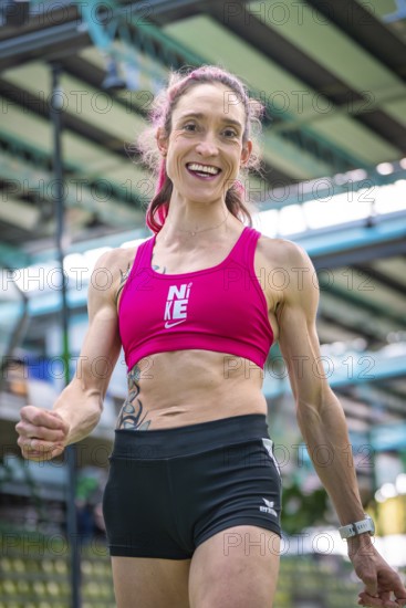 Sporty dressed woman with a smile indoors showing fitness and energy, middle distance runner