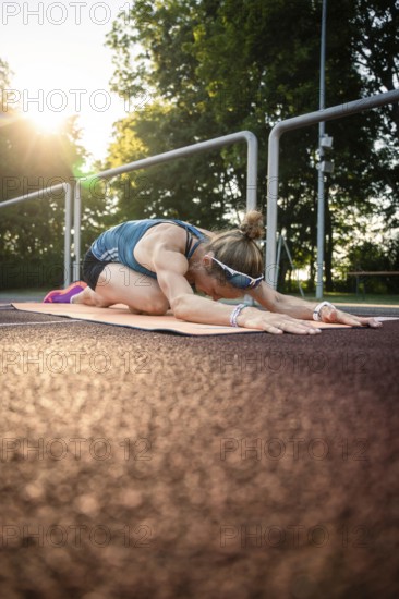 Woman in yoga pose on mat at sunset, natural environment, emphasizing peace and relaxation, middle