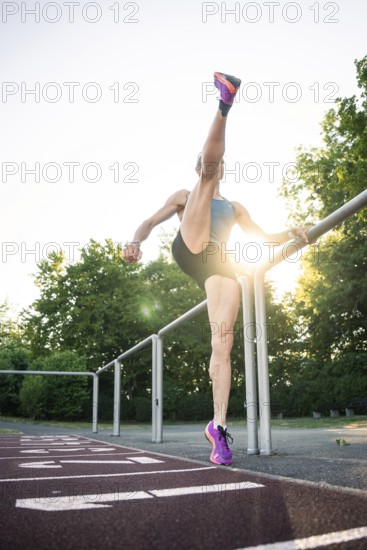 Woman steps high on a running track near a railing, middle distance runner Katharina Jaiser,