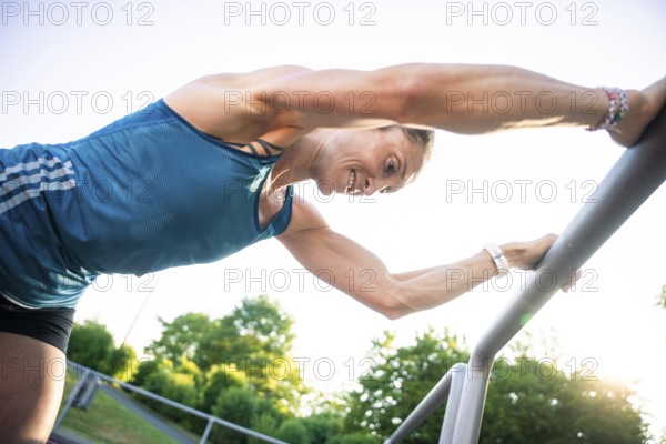 Woman bends over outdoor railings, concentrates on intensive training, middle distance runner
