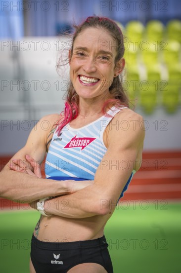 Self-confident sportswoman with pink hair in stadium, smiling friendly, middle distance runner