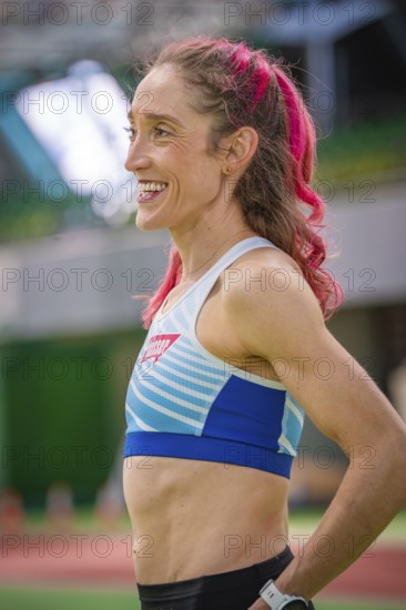Smiling sportswoman with pink hair in stadium, looks fit and friendly, middle distance runner