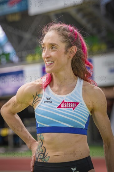 Smiling sportswoman with pink hair and blue sportswear in stadium, middle distance runner Katharina