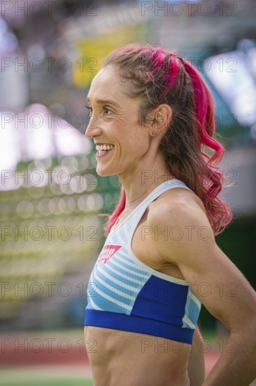 Happy sportswoman with pink hair in the stadium. Smiles and looks satisfied, middle distance runner