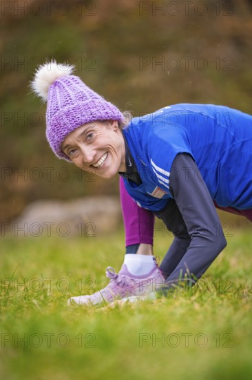 Woman wearing colorful winter clothes smiling in a meadow, relaxed and joyful atmosphere, middle