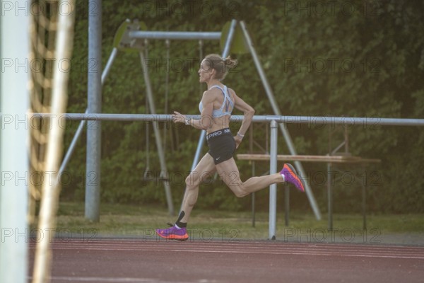 Woman runs intensively and concentrated along the track, middle distance runner Katharina Jaiser,