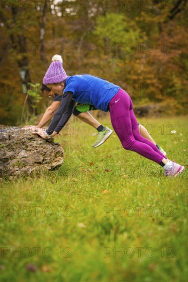 Two people doing outdoor sports exercises on rocks in autumn terrain, middle distance runner