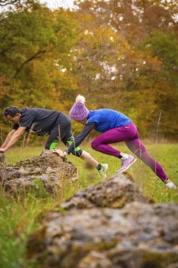 Man and woman training over rocks in an autumn park, middle distance runner Katharina Jaiser,
