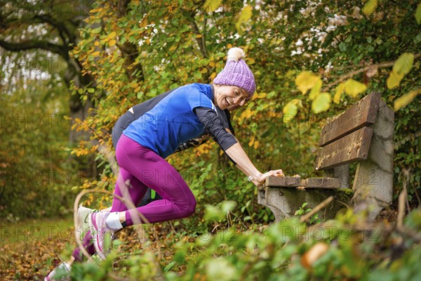 Woman stretching on a bench in an autumnal park, middle distance runner Katharina Jaiser,