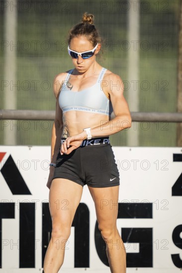 Athlete checks her watch on the sports field, focused and prepared, middle distance runner