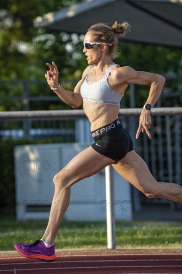 Athlete in full sprint on a running track, with energetic attitude in daylight, middle distance