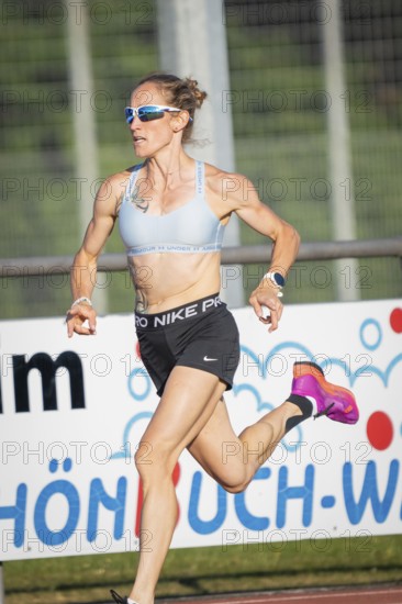 Focus on a sprinting athlete in sporty clothes in sunny weather, middle distance runner Katharina