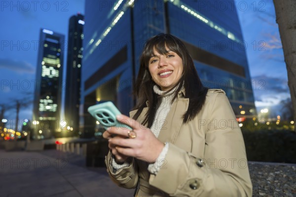 Young professional woman smiling while using her smartphone for networking and social media in a