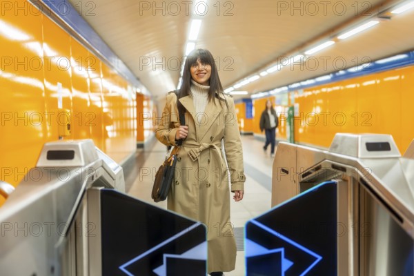 Young woman confidently walking through an automatic turnstile at a modern subway entrance, smiling