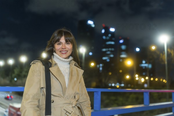 Young woman wearing a trench coat and turtleneck sweater smiling confidentially, standing outdoors