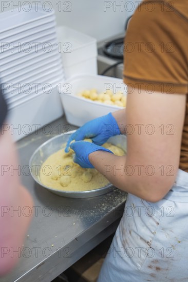 Person breading round foods in a bowl in a kitchen situation, chocolate quail eggs, Easter