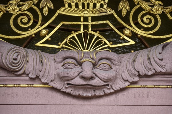 A stone face surrounded by ornaments and decorations, detailed view of the main portal of the
