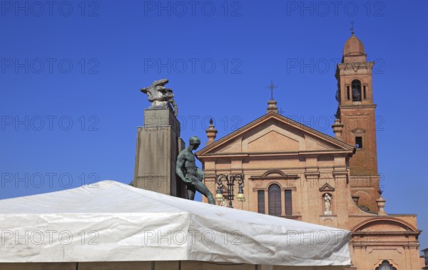 Monument with a statue in Piazza Unita and the Santo Stefano Collegiate Church in the city of