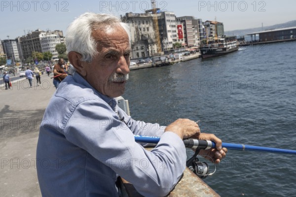 Istanbul, Turkey. June 23rd 2025. An old Turkish man fishing on the Galata Bridge near Karikoy