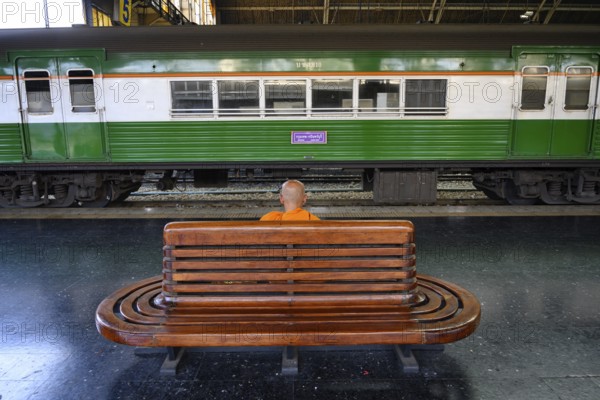 A Buddhist monks waits for his train on the platform at Hua Lamphong Railway Station, Bangkok,