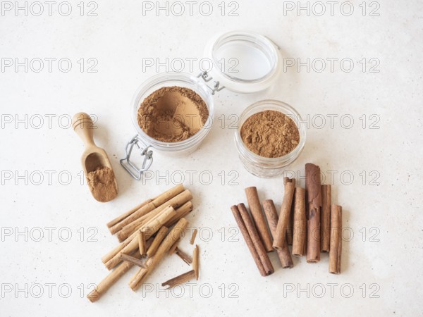 Cinnamon sticks, cassia and ceylon, with ground powder in jars and a wooden scoop