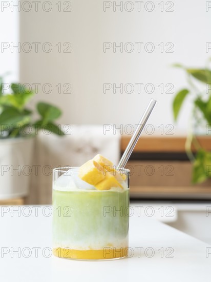Iced matcha latte with tropical mango, milk, and clear straw in a glass