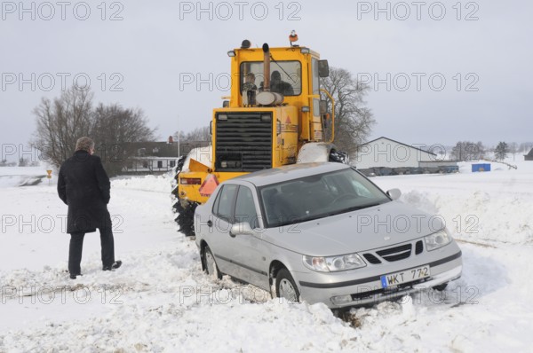 Car stuck in snow gets help from a loader to get free in Skurup municipality, Skåne county, Sweden,
