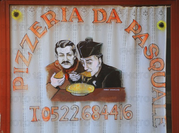 Italy, village of Brescello, advertisement for Pizzeria Pasquale, with a picture of Don Camillo and