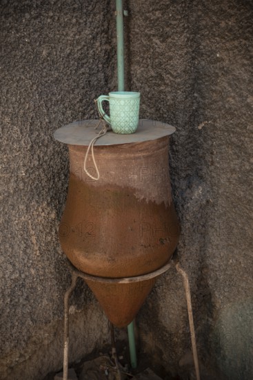 A local clay public clean water drinking fountain with plastic mug, along the Nile River in Upper