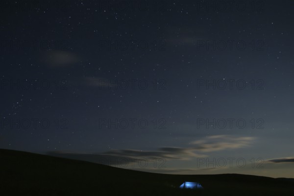 Illuminated tent stands alone in Mongolian steppe under starry sky at night, Nömrög National Park,