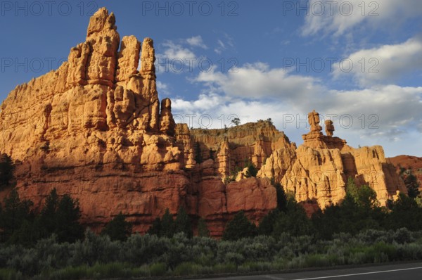 Massive red rock formations in sunlight under a blue sky with clouds, Bryce Canyon National Park,