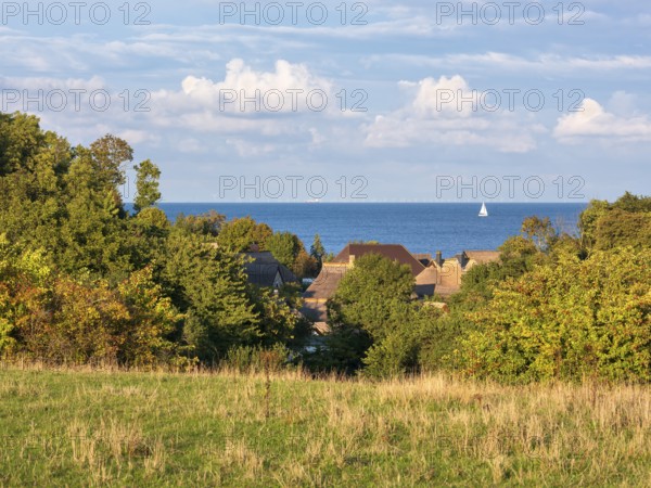 View over the thatched roofs of the fishing village of Vitt to the Baltic Sea, a sailboat on the